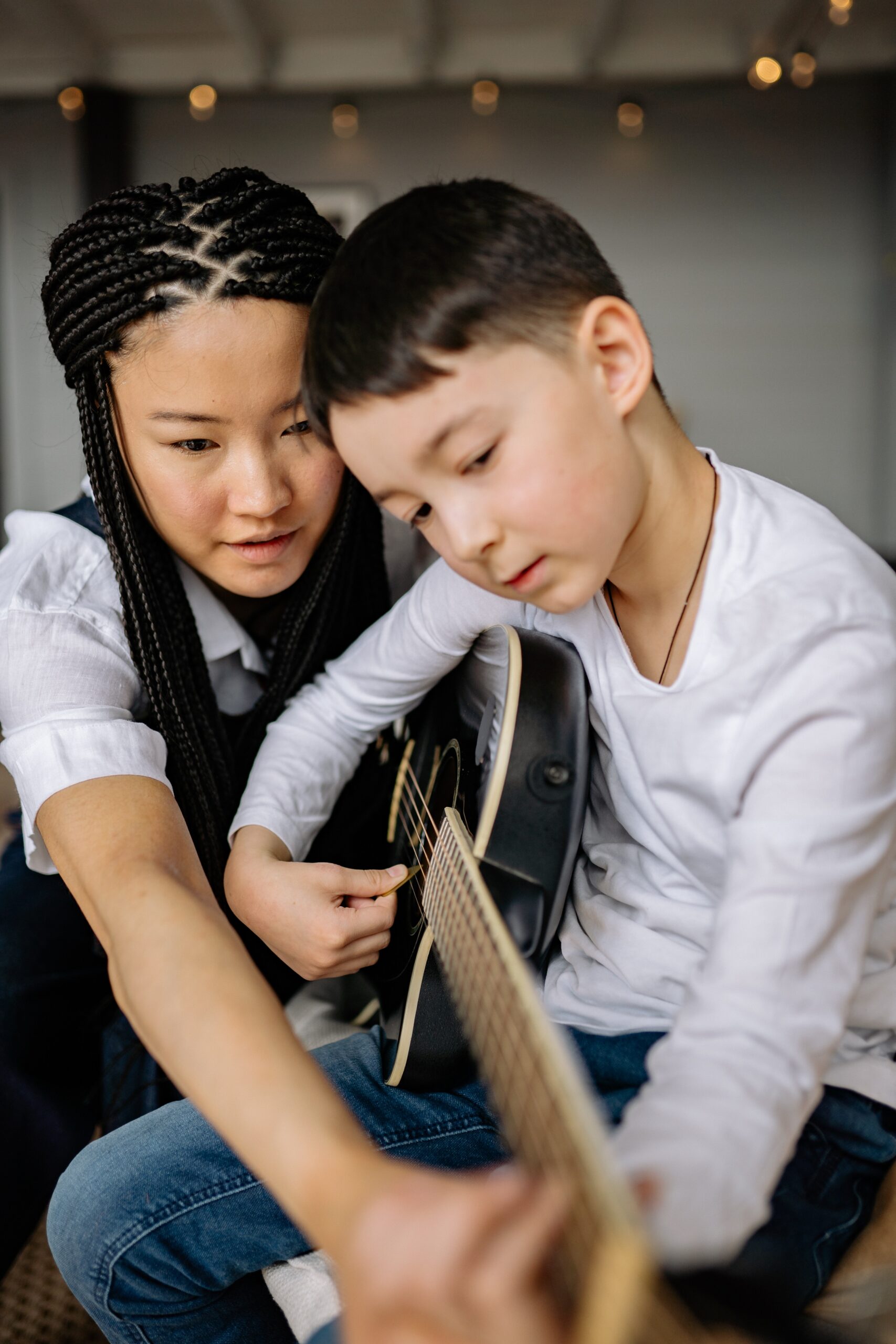 instructor guiding young student holding guitar taking guitar lesson